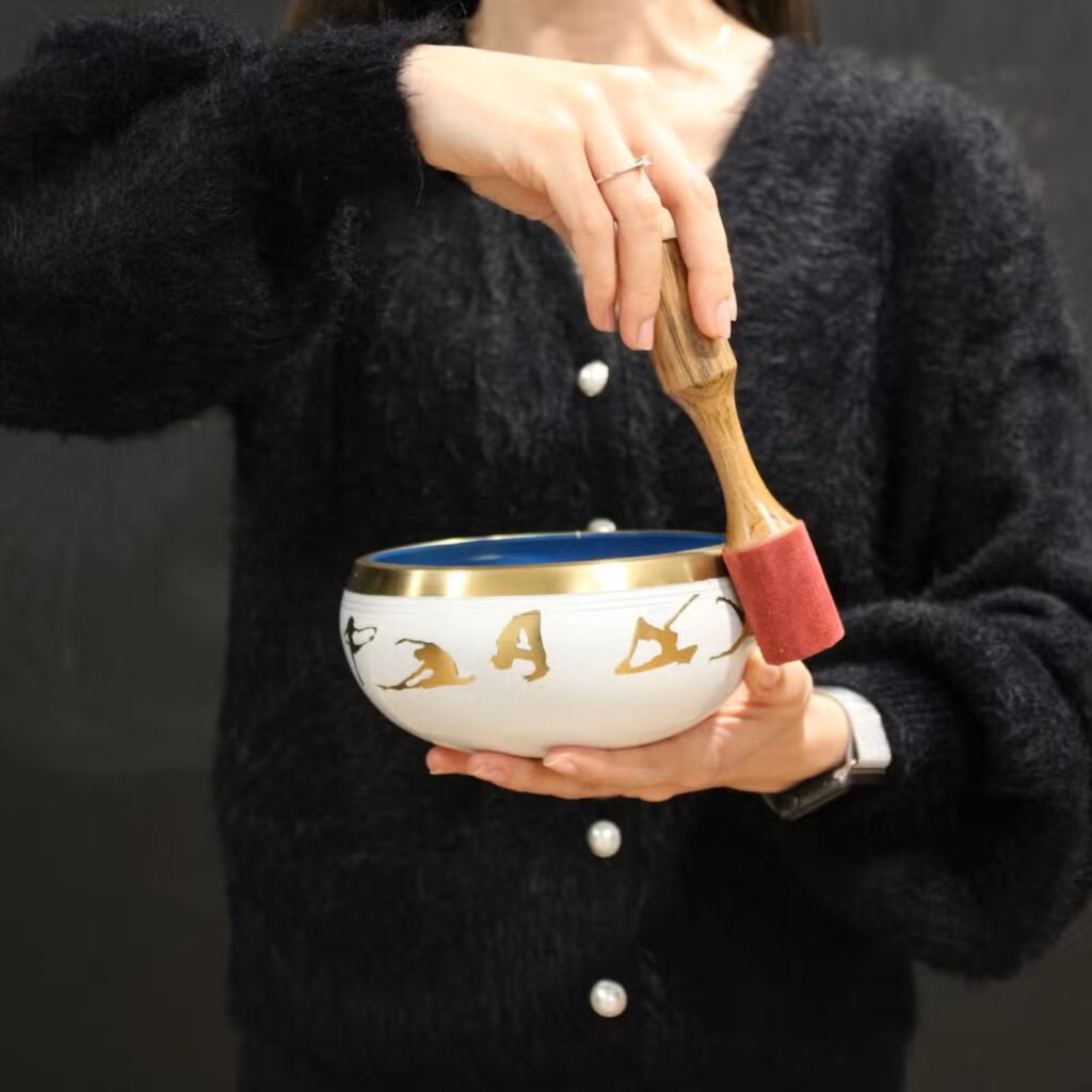 Brass singing bowl being played with a wooden striker
