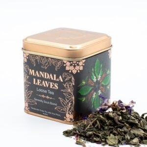 Decorative tin of Mandala Leaves loose tea with herbal blend, featuring green leaves and dried tea leaves beside the container, ideal for tea lovers and gift buyers.
