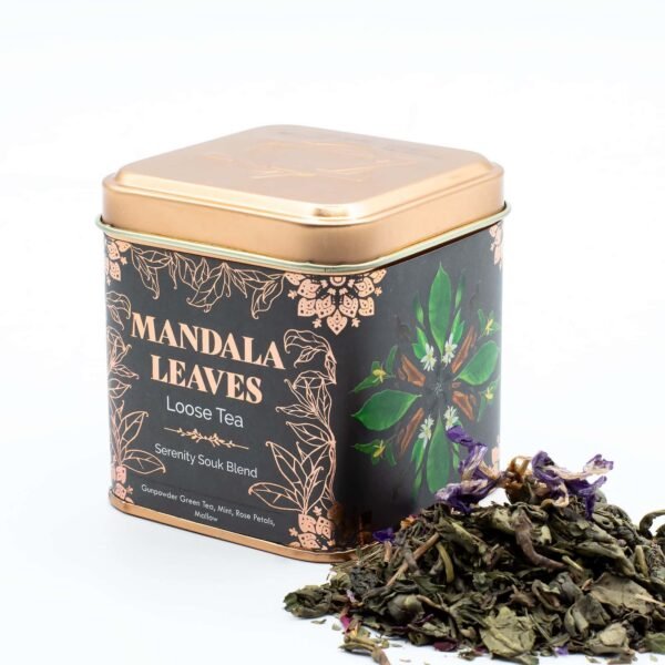 Decorative tin of Mandala Leaves loose tea with herbal blend, featuring green leaves and dried tea leaves beside the container, ideal for tea lovers and gift buyers.